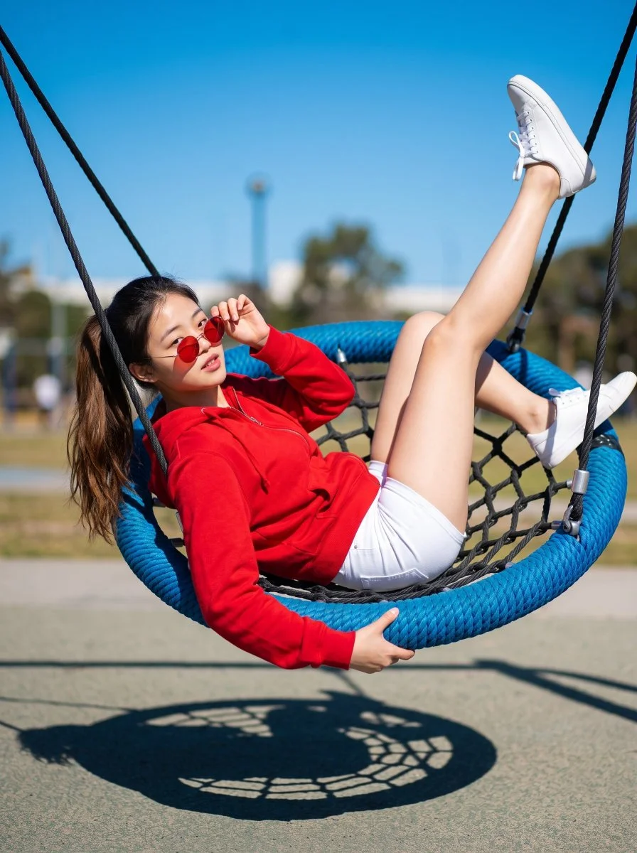 Playful woman balances on web swing with leg raised high