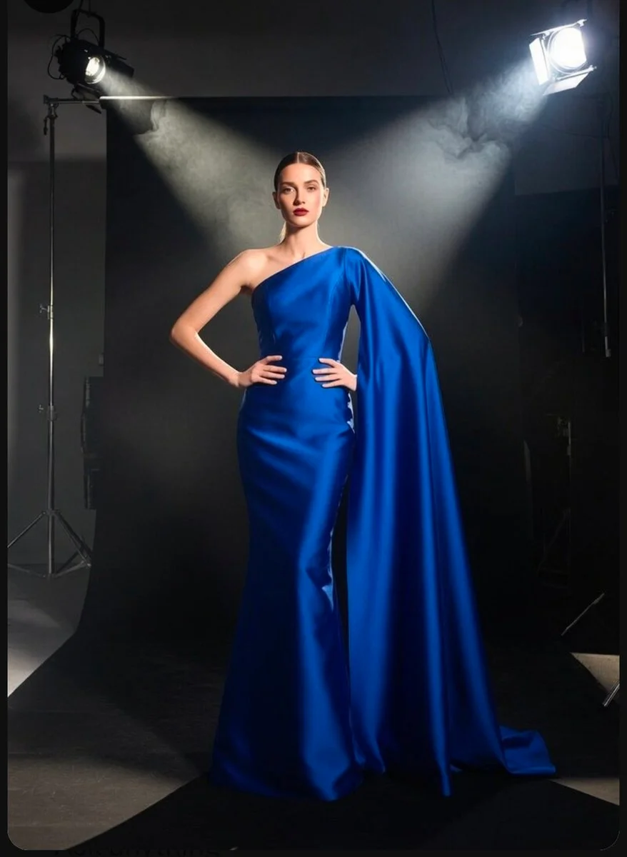 Royal blue fabric swirls as the model moves beneath cinematic spotlight
