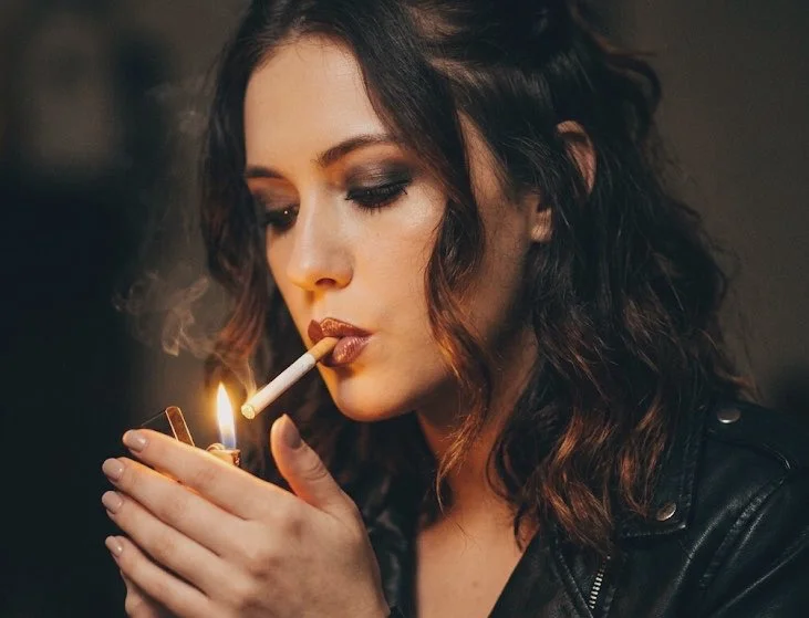 Seductive portrait of a woman lighting a cigarette at night