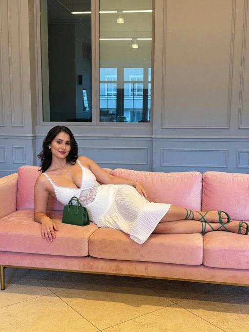 Seductive pose on pink sofa with green handbag in daylight