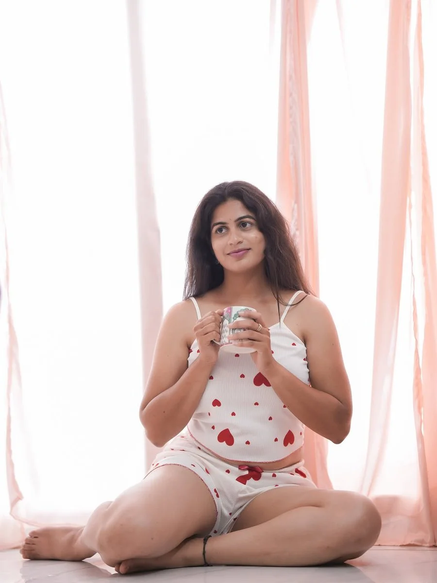 She smiles gently while holding a white mug in white lace