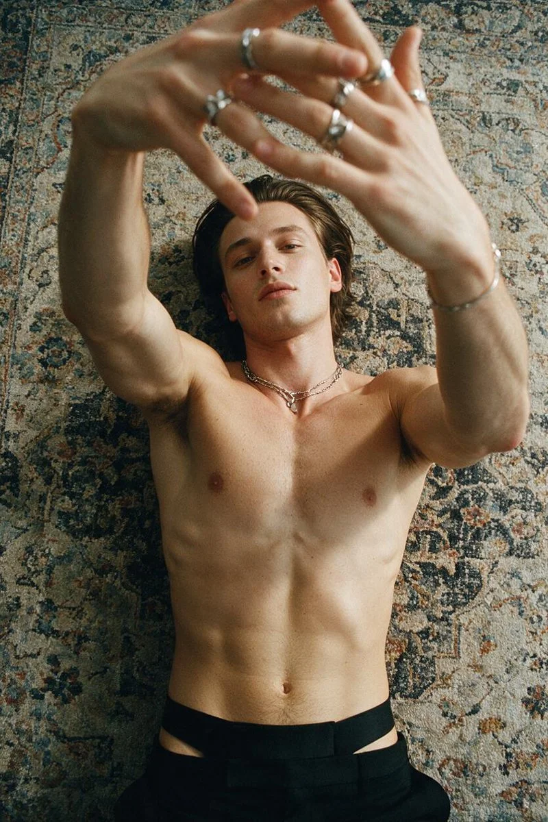 Shirtless Man Lies on Vintage Rug with Hands Framing Face