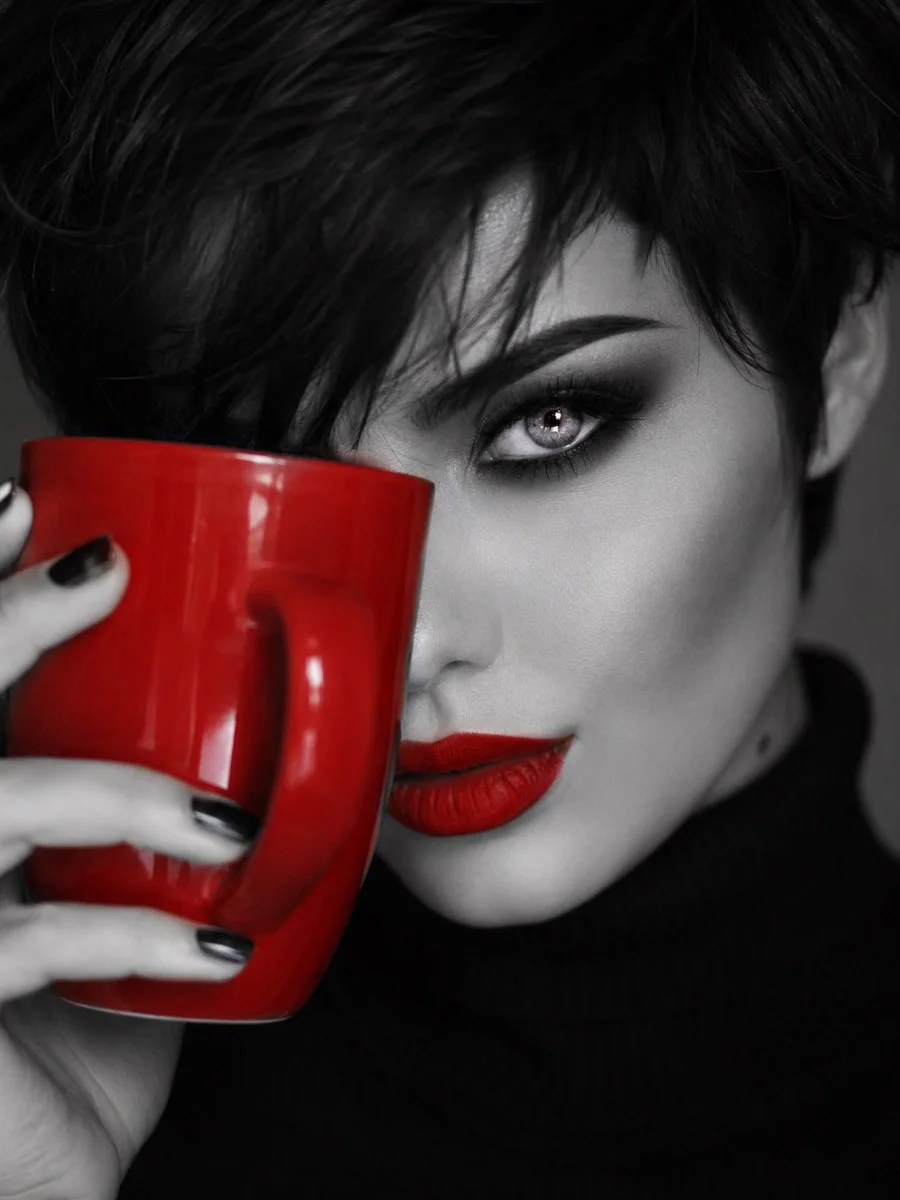 Smokey eyes and red ceramic cup frame her intense gaze