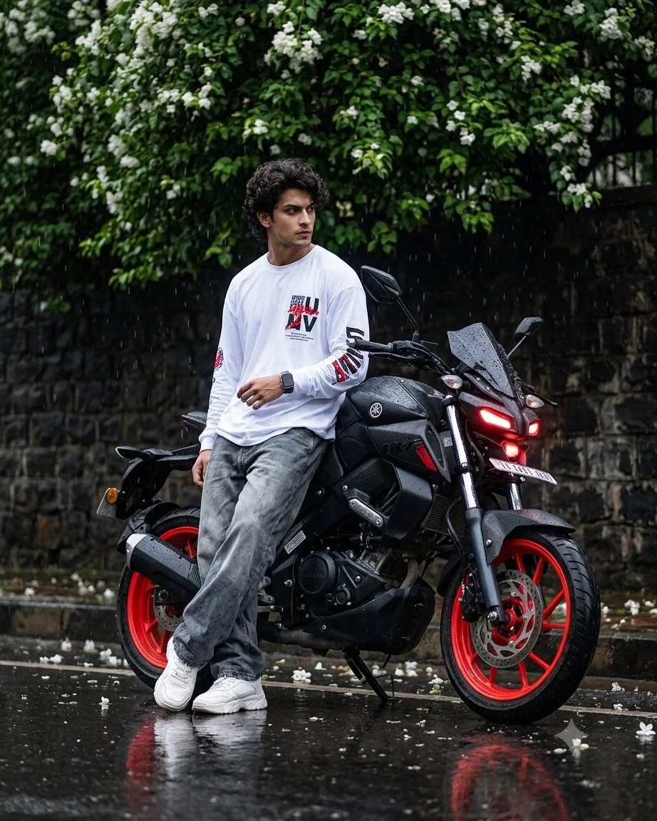South Indian boy leans on a matte black Yamaha in the rain