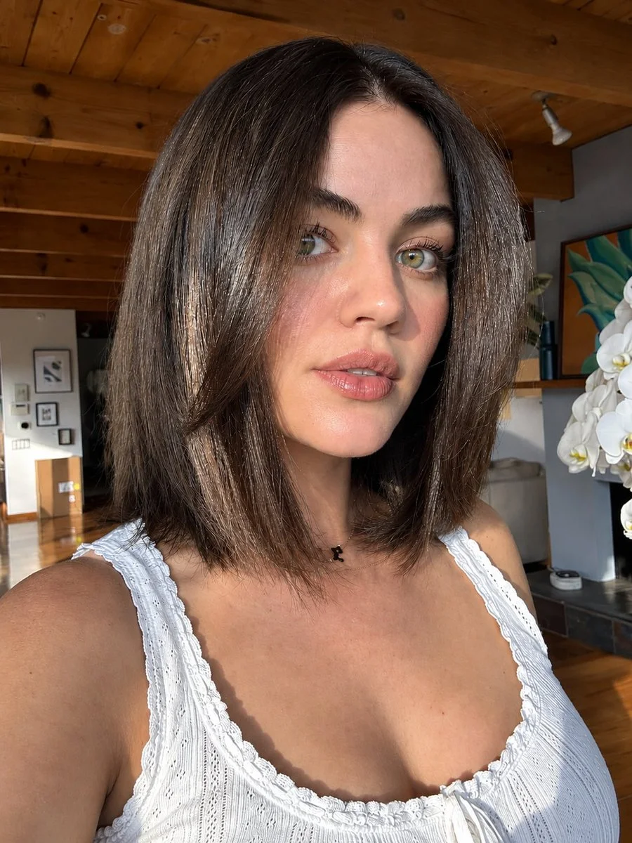 Sunlit close-up selfie captures woman's natural beauty in warm home light
