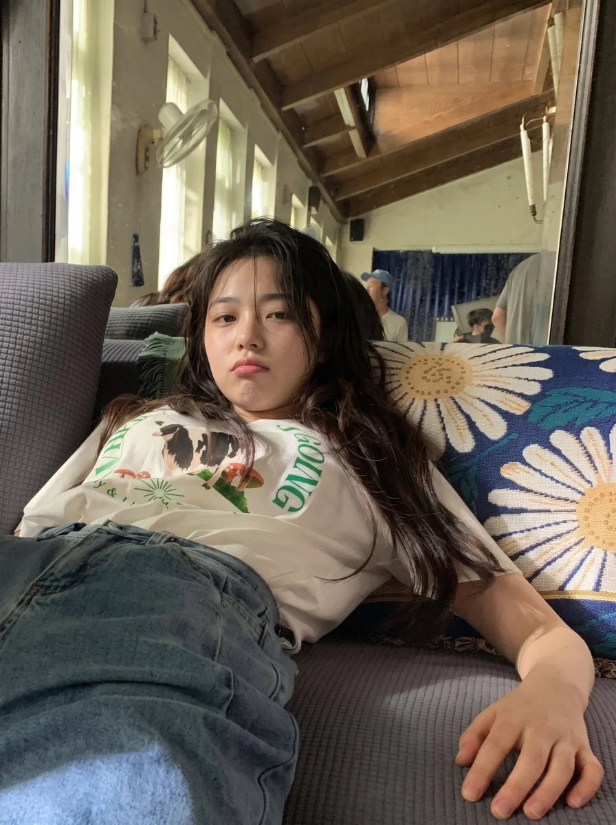 Tired young woman in oversized tee slumps on sofa after huge meal