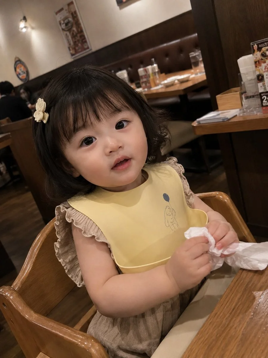 Toddler girl sits in high chair at cozy Japanese restaurant