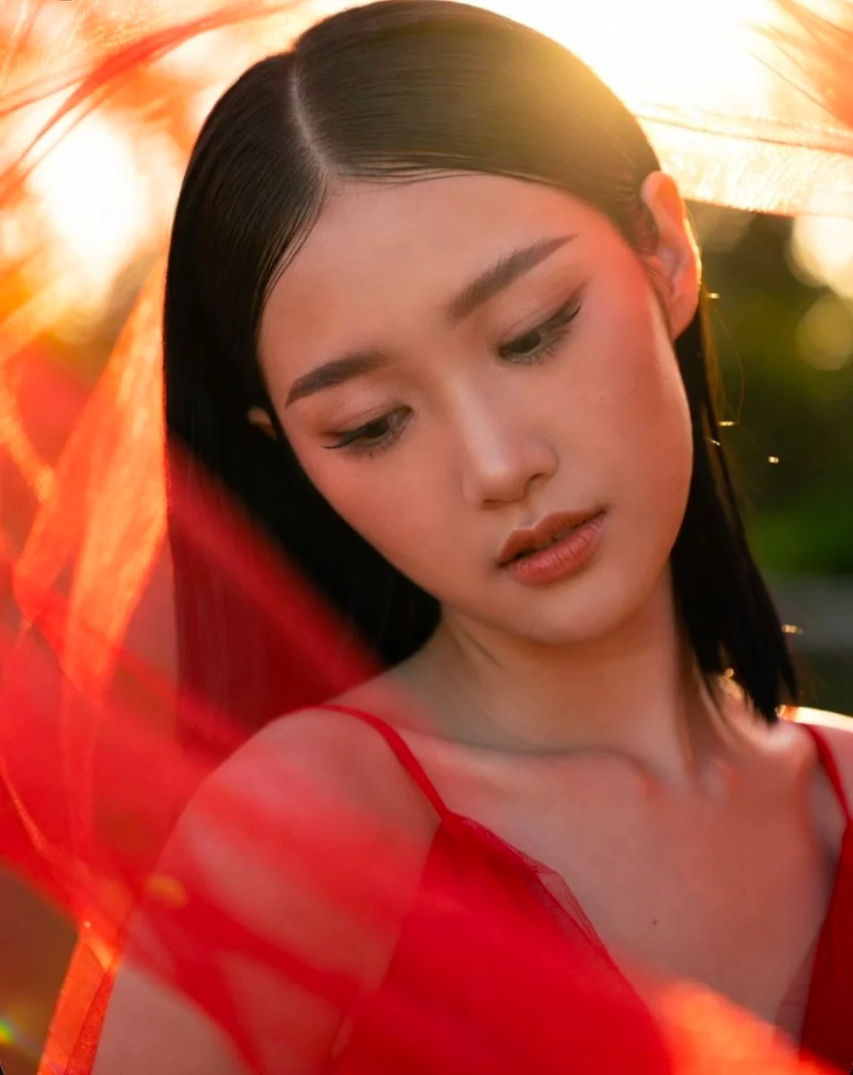Warm rim light caresses contemplative face through red veil