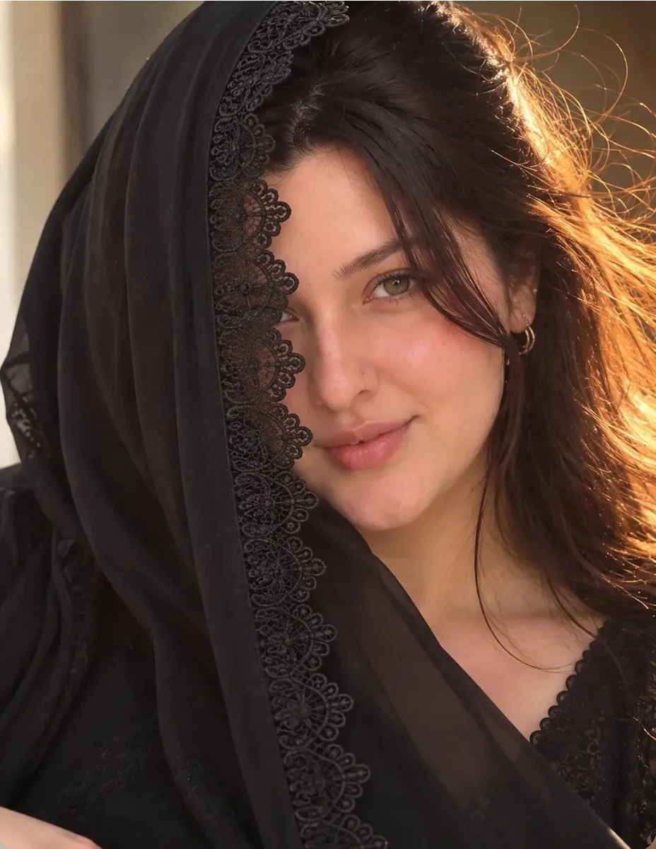 Warm sunlight highlights a serene woman in traditional black attire