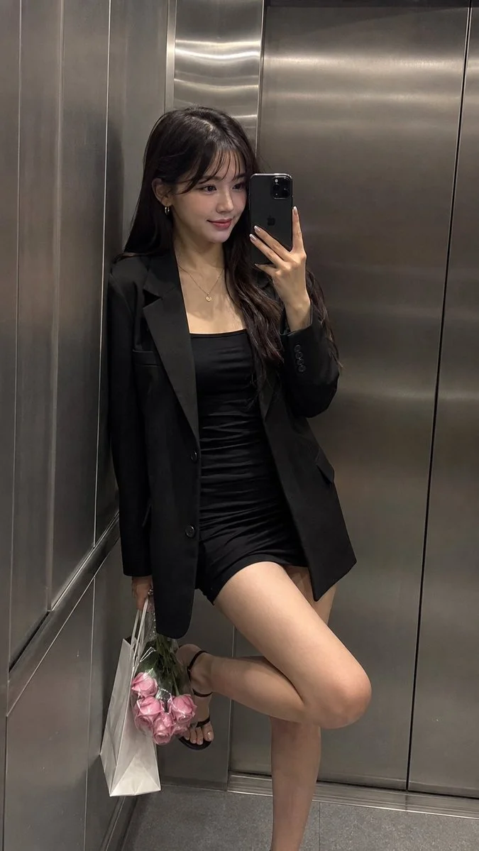 Woman in black blazer poses with roses in elevator mirror selfie