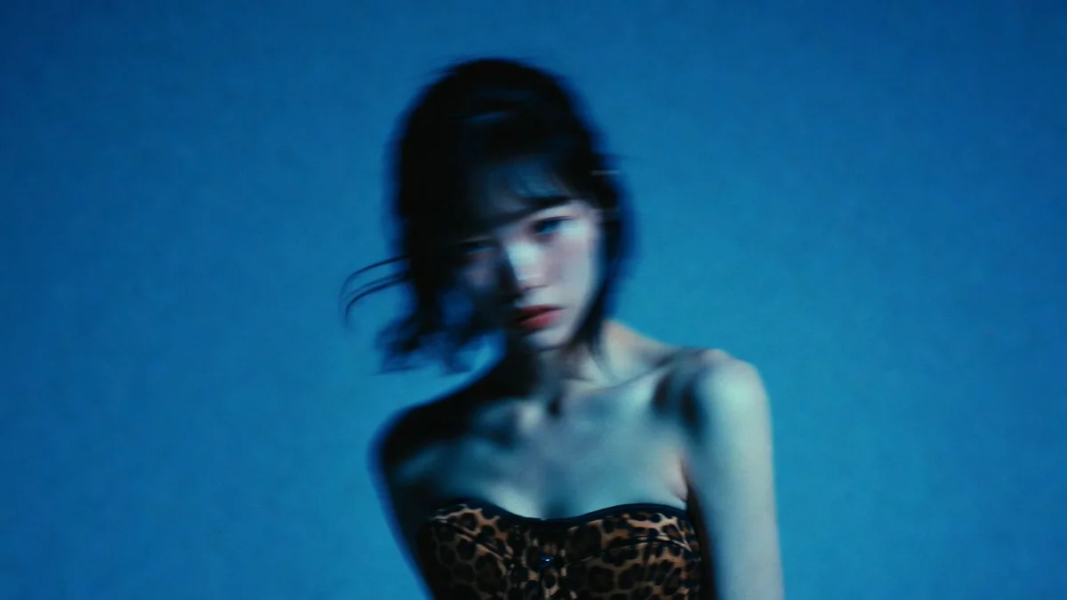 Woman in leopard corset poses against blue seamless backdrop
