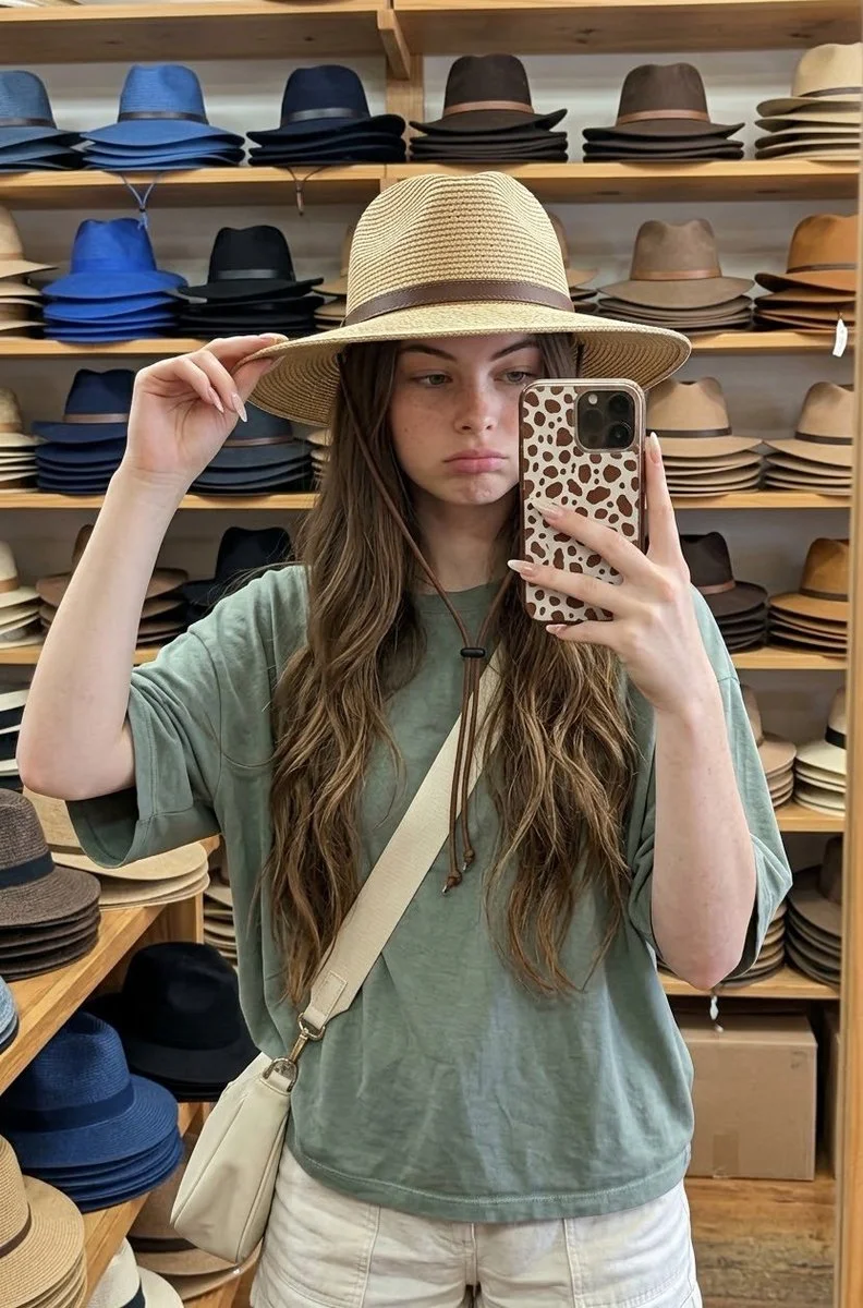Woman in Straw Hat Takes Selfie Inside a Hat Shop