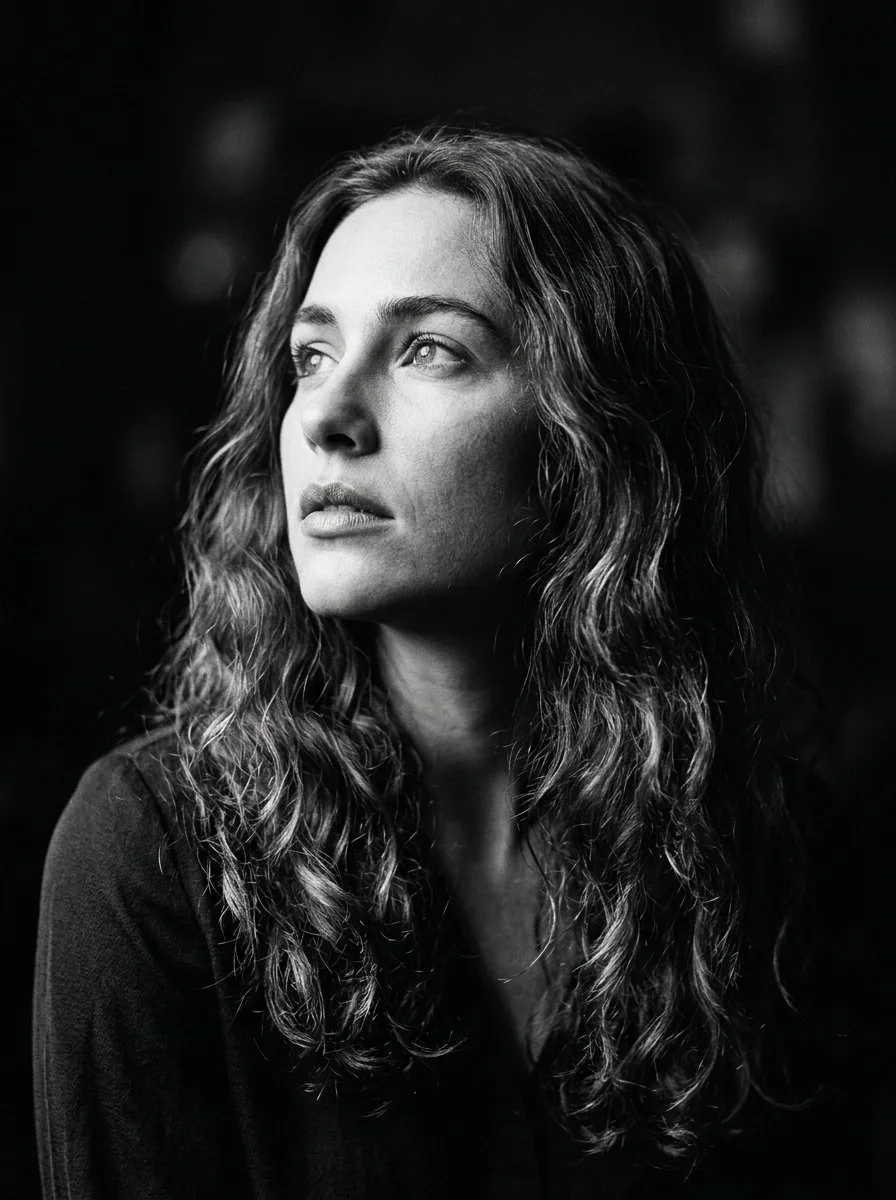Woman with wavy hair gazes upward in dramatic chiaroscuro portrait