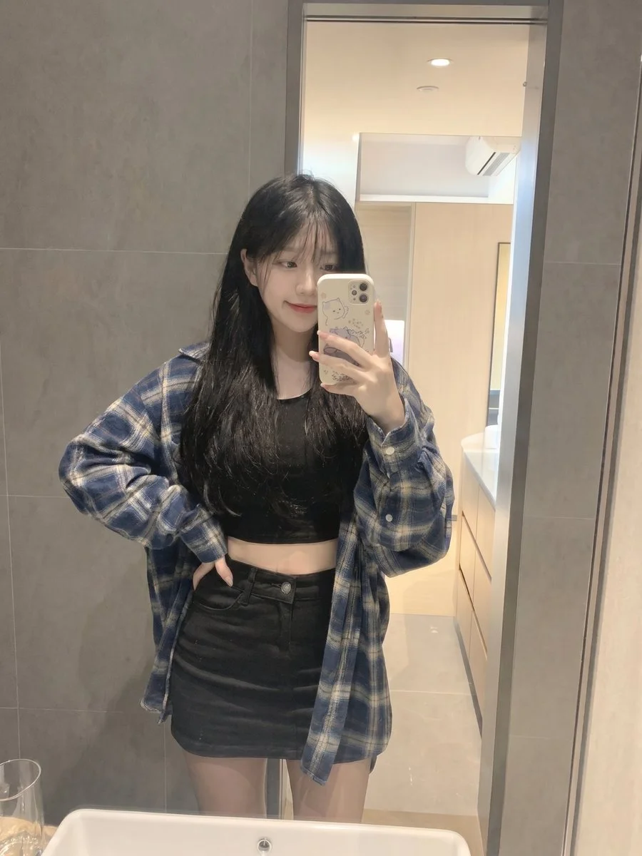 Young girl in plaid flannel takes a playful mirror selfie