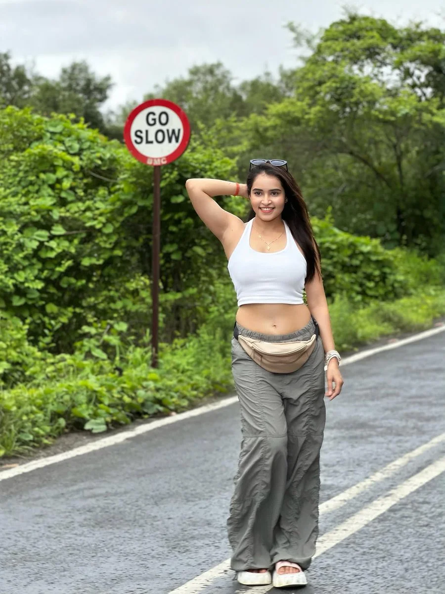 Young Indian woman poses on wet road with sunglasses atop head