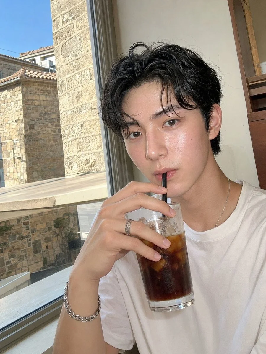 Young man sips iced coffee by sunlit café window