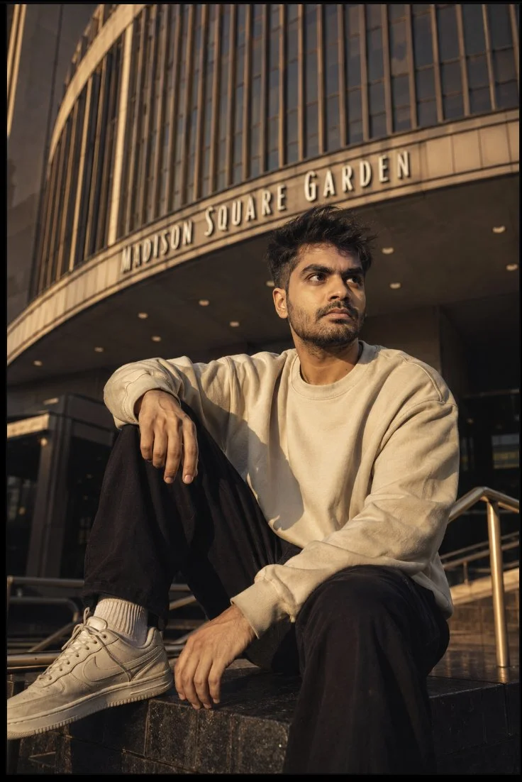 Young man sits calmly at arena entrance during golden hour.