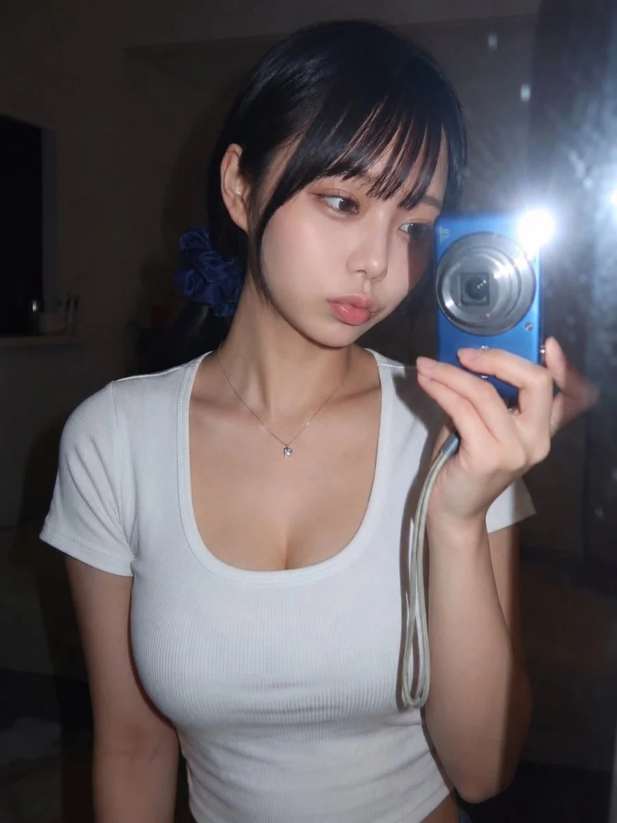 Young woman captures a mirror selfie with bright camera flash