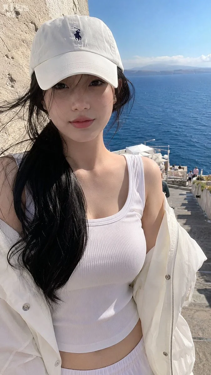Young woman in white cap and jacket at seaside viewpoint