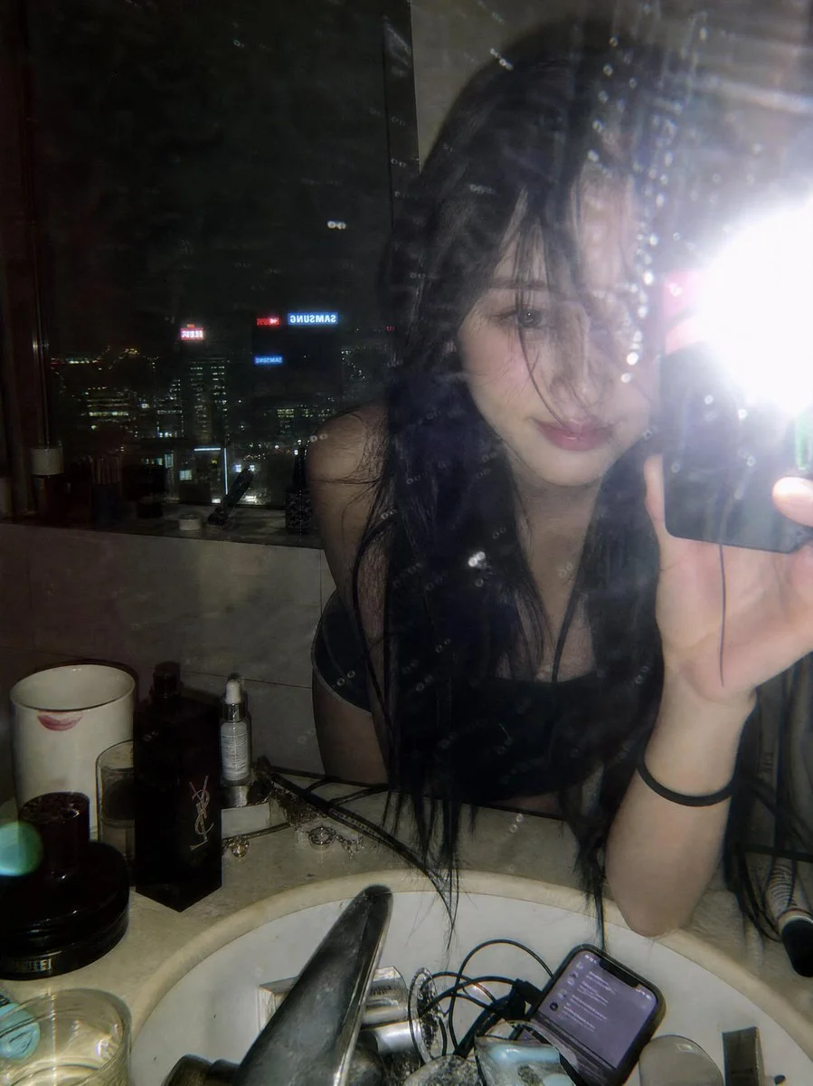 Young woman leans over marble sink for a flash mirror selfie