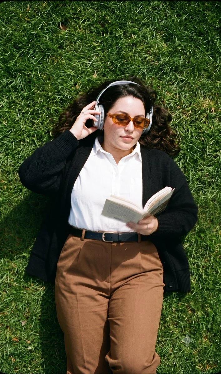Young woman reads on grass with vintage style and headphones