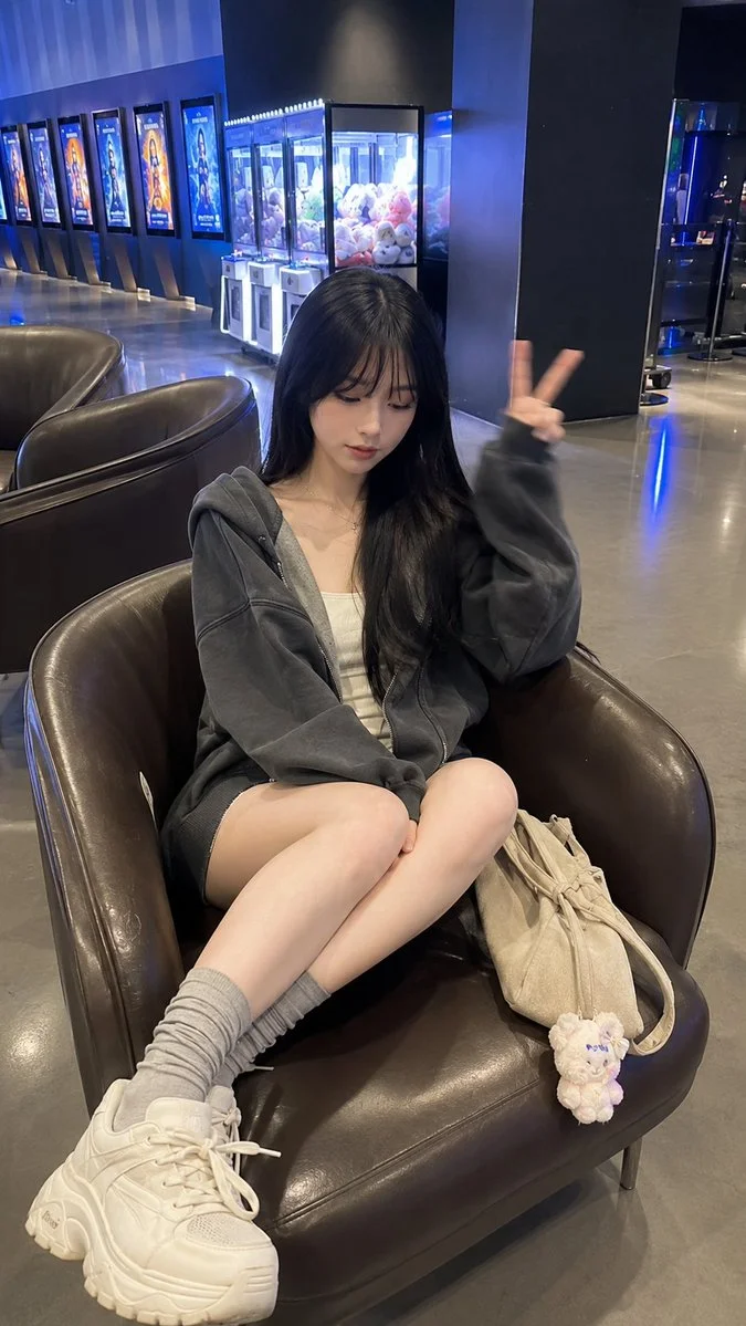 Young woman rests in cinema lobby with peace sign gesture