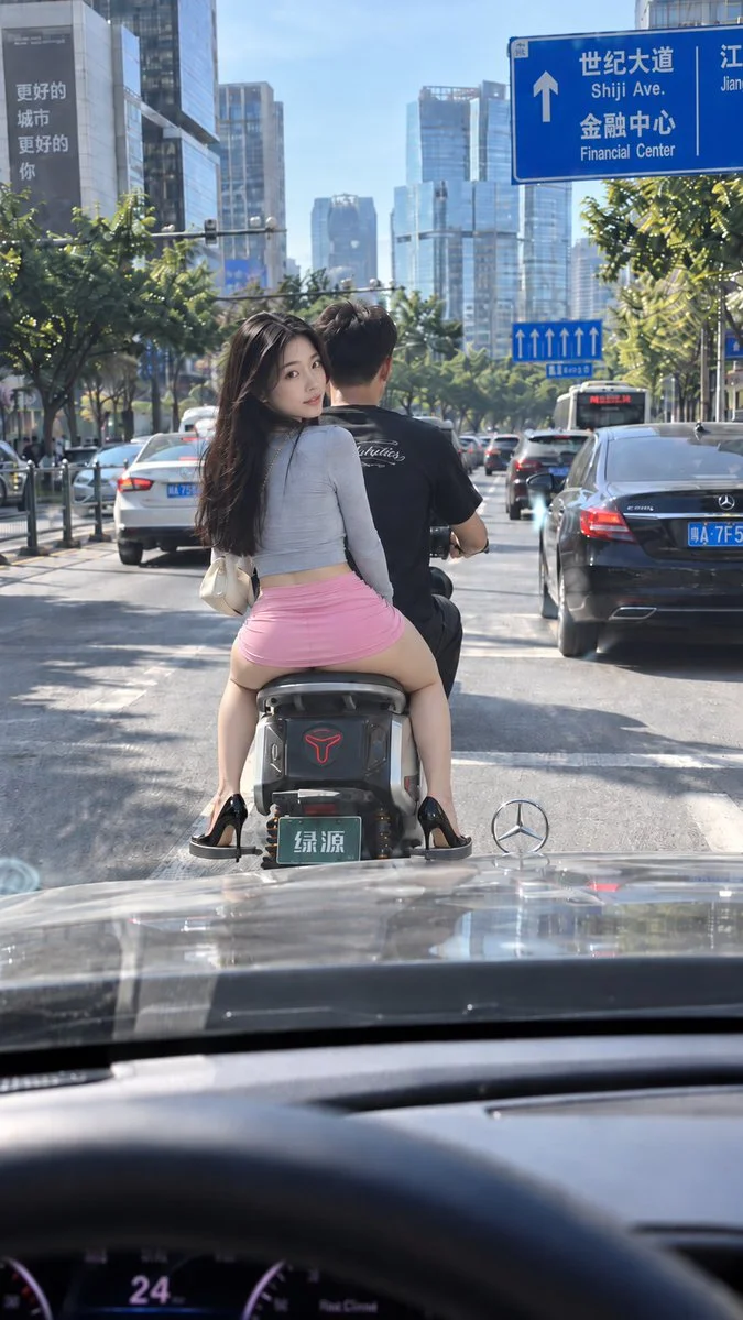 Young Woman Turns Back on Scooter in Busy City Traffic