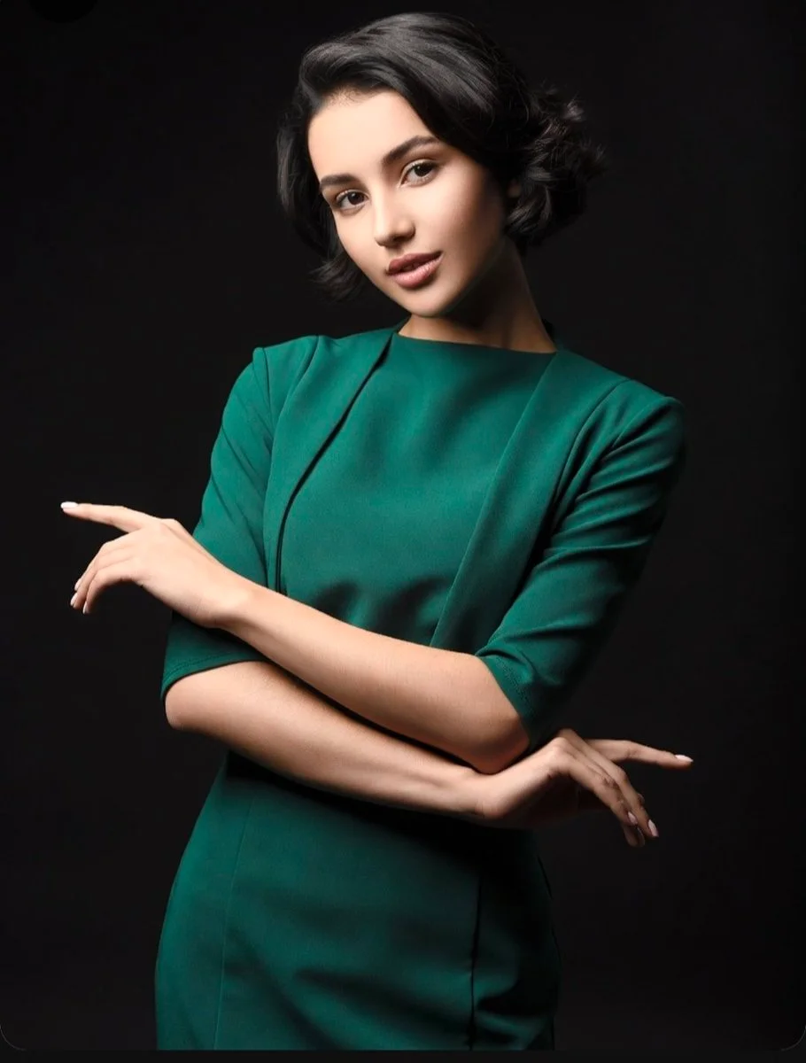 Young woman with dark hair poses gracefully in emerald gown